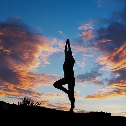 femme en position de yoga sur un soleil couchant