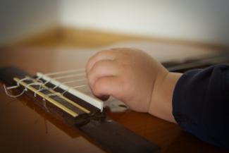 gros plan d'une main d'un enfant sur une guitard